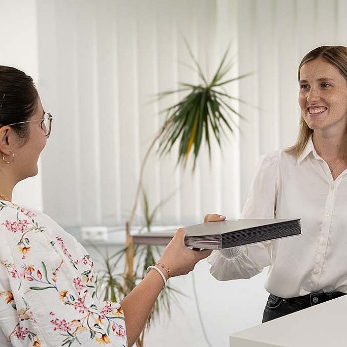 Annika from STRATEC handing a folder over to another colleague 
