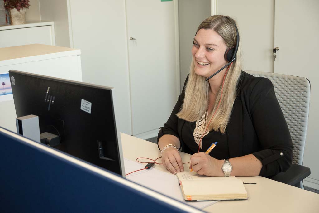 Nicole from STRATEC sitting in her office during a call while noting something into her notebook