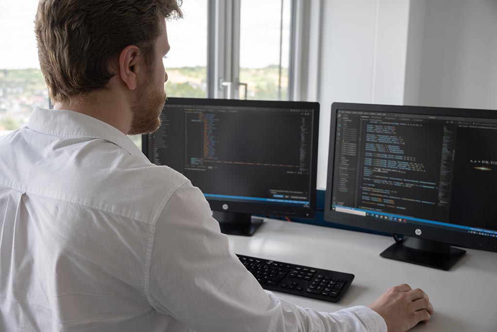 Ilya from STRATEC looking into two monitors in front of him showing several software codes