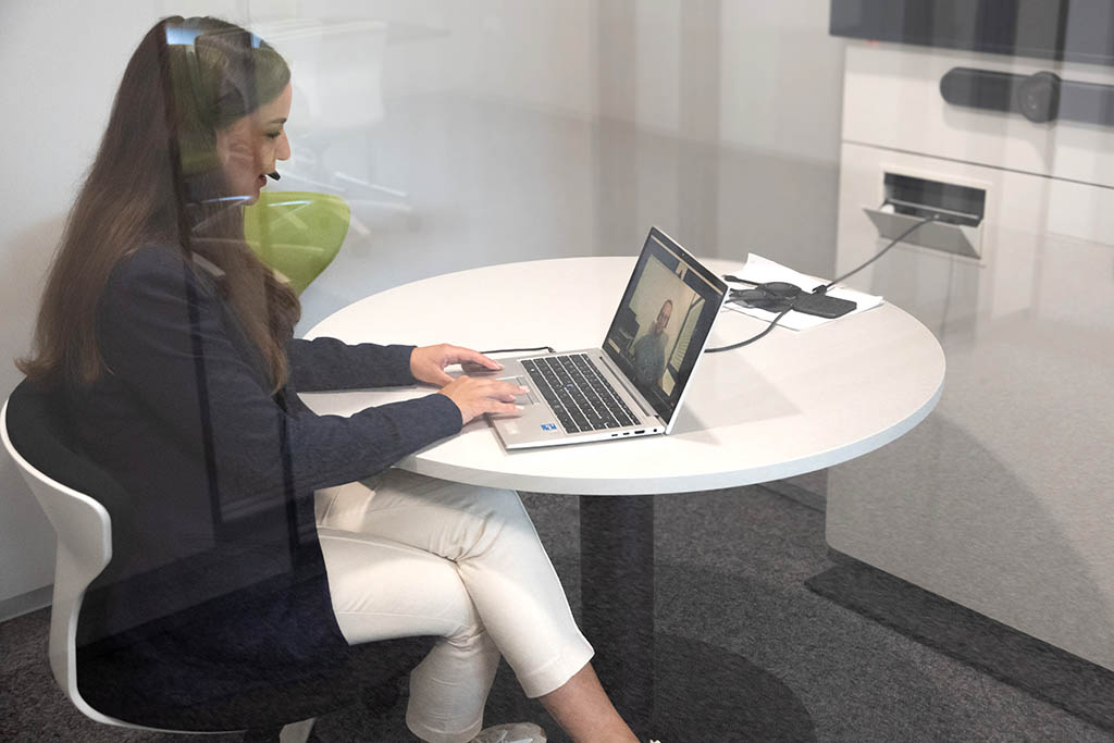 Hanna from STRATEC sitting in a closed office space during a Zoom call with headphones behind a glass door