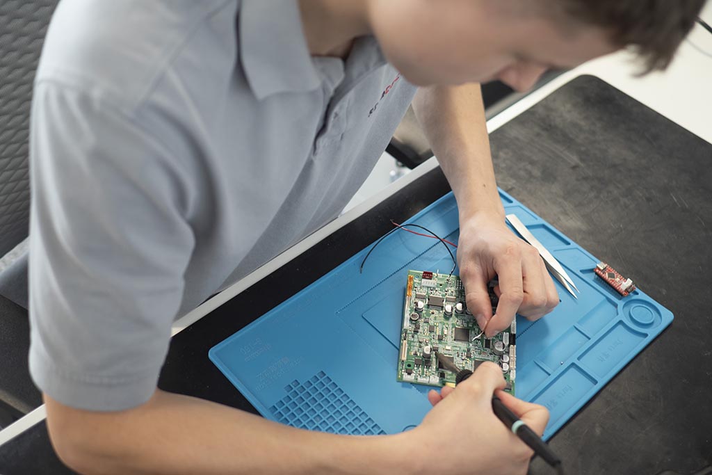 Yoann from STRATEC working on a module above a blue and black matt on a table
