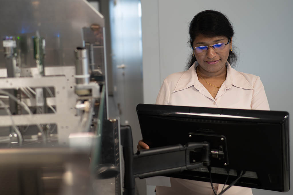 Grace Mary from STRATEC standing in front of the monitor attached to an instrumentation prototype
