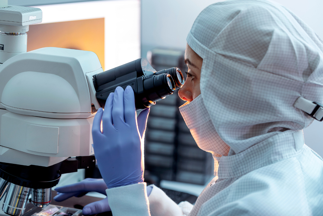 Female lab technician looking into the microscope in the STRATEC production site in Austria