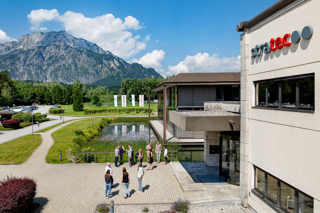 Outside view of the STRATEC office in Austria with a mountain and lake in the background