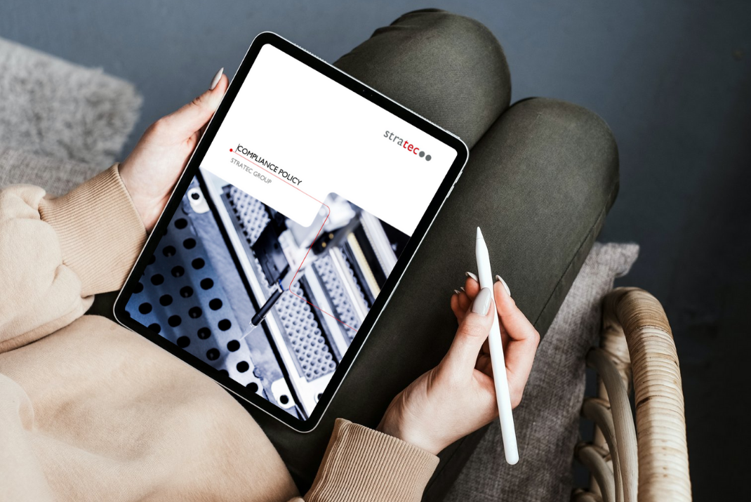 Woman with a tablet in her hand showing the corporate compliance policy page of STRATEC