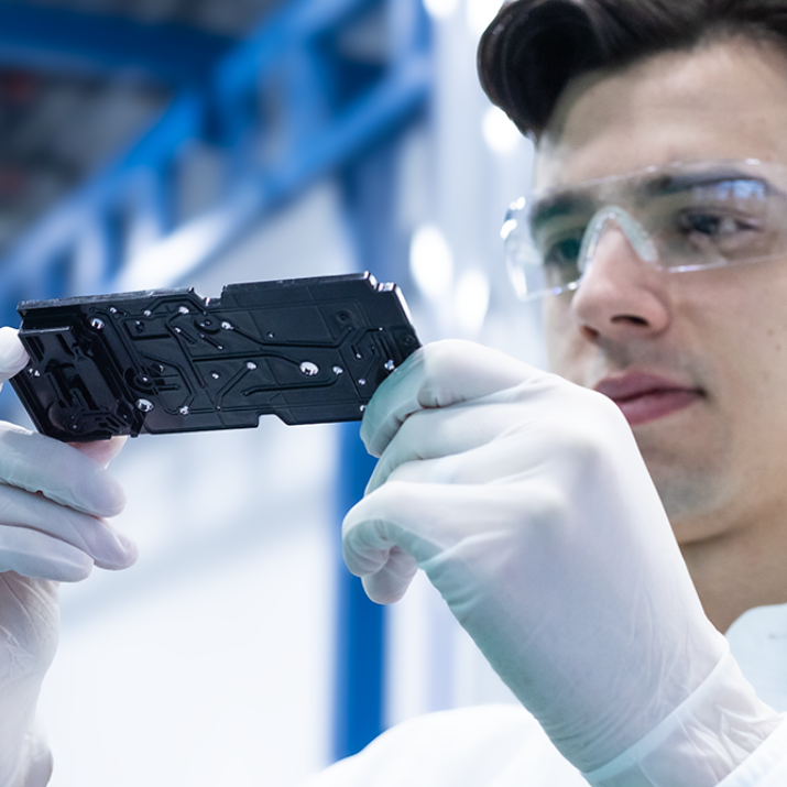 Natech employee with safety gloves and glasses inspecting an assembly piece