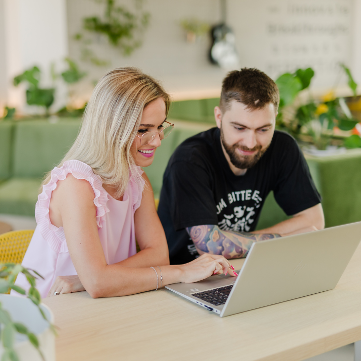 Two employees looking into a laptop screen in the open office space in the Romanian site of STRATEC