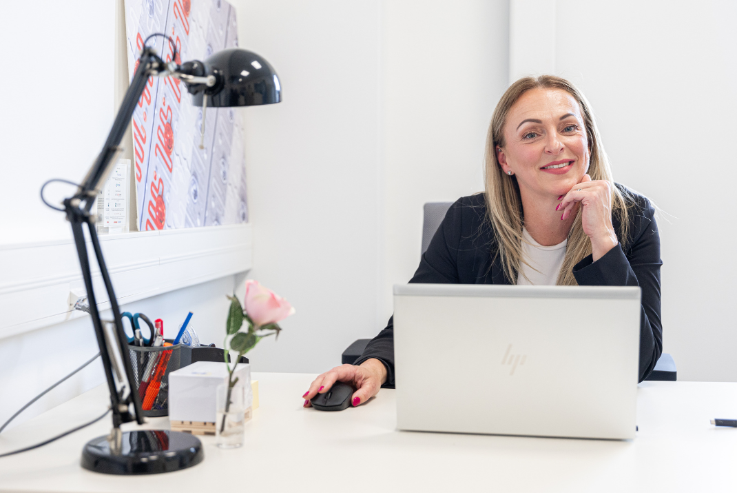 Évi from Diatron sitting at her desk with a laptop
