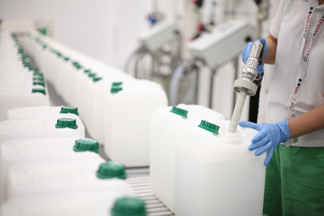 A Diatron employee filling up white tanks with green lids