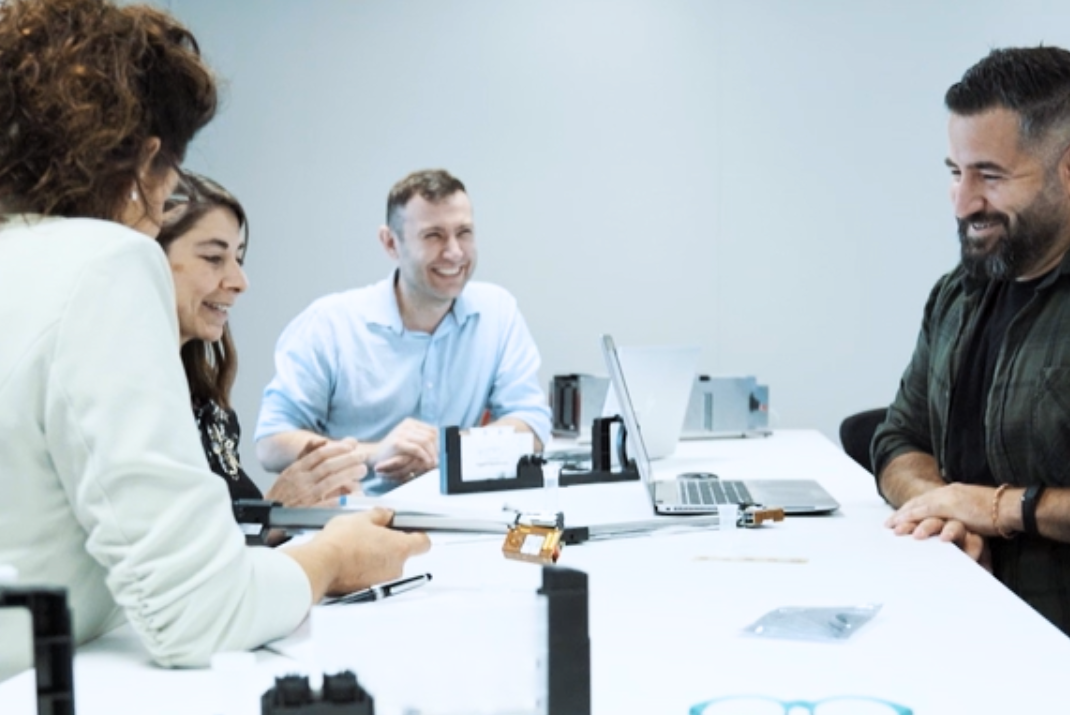 STRATEC employees sitting on a desk in the office laughing