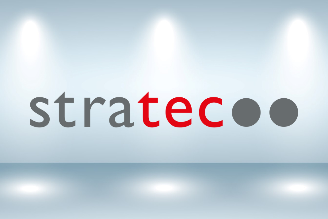 STRATEC logo on a wall with three lights from the top shining on it