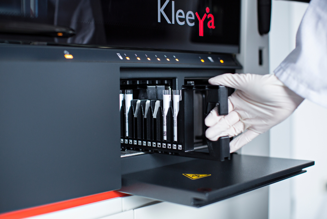 Laboratorian with white safety gloves pulling out the reagent rack from the chemiluminescence analyzer KleeYa by Diatron