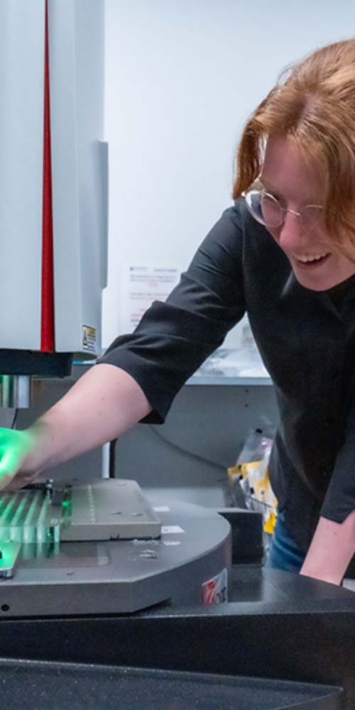 Employee putting her hand forward to touch something on the laboratory device